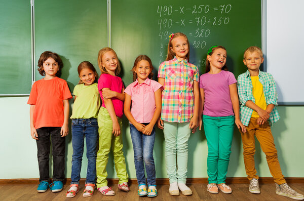 Kids stand in line near the blackboard