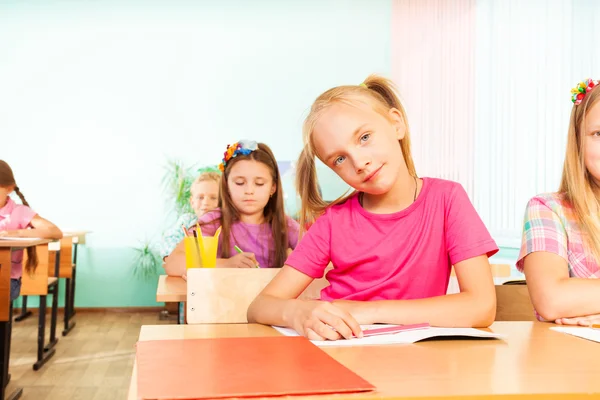 Smiling girl sits at desk — Stock Photo, Image