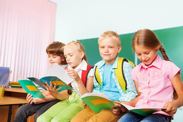 Escolares sentados com livros didáticos — Fotografia de Stock