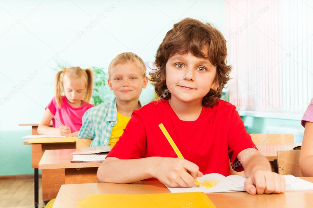 Cute boy looking straight and writing