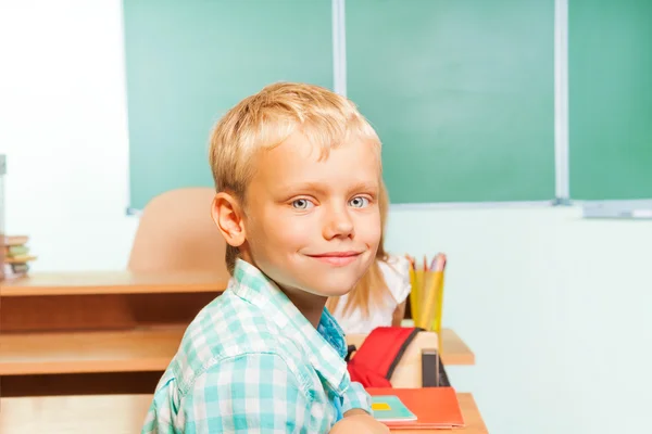 Boy gülümseyerek masa başında oturur — Stok fotoğraf