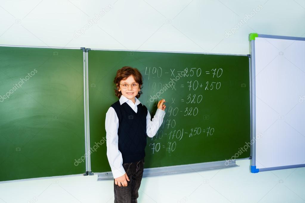 Boy with glasses near blackboard