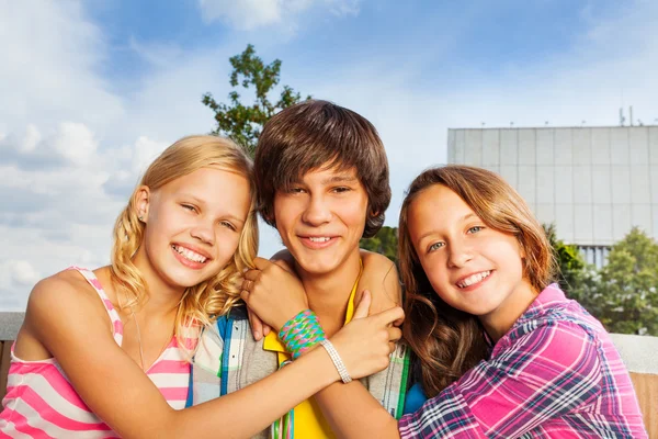 Girls embracing boy's neck a — Stock Photo, Image