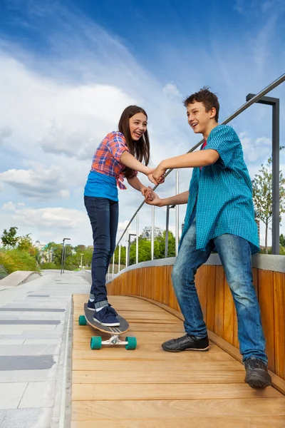 Muchacho enseñando chica a montar monopatín — Foto de Stock