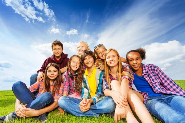 Amigos sentados en el prado verde — Foto de Stock