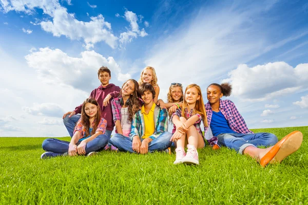 Amigos sentados en el prado verde — Foto de Stock