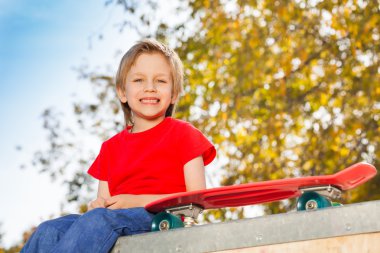 Sarışın çocuk kaykay ile oturan