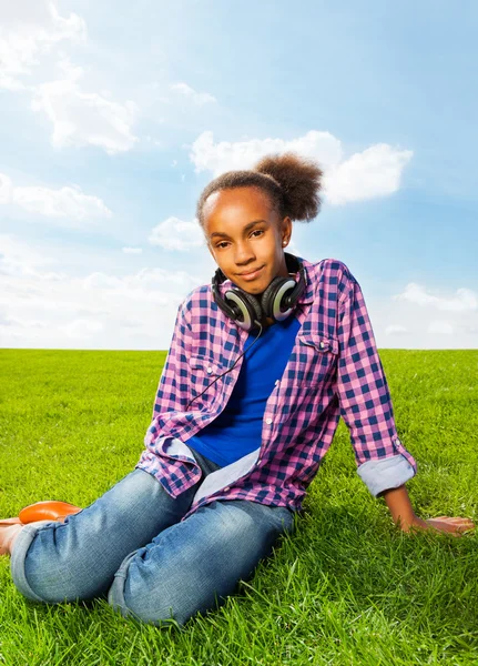 Африканская девушка сидит на зеленой траве — стоковое фото