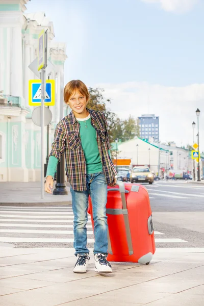 Smiling boy holds red luggage — Stock Photo, Image