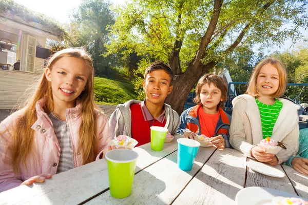 Les enfants boivent du thé et mangent des cupcakes — Photo