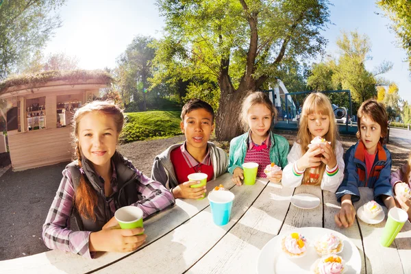 Les enfants boivent du thé et mangent des cupcakes — Photo