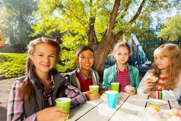 Les enfants boivent du thé et mangent des cupcakes — Photo