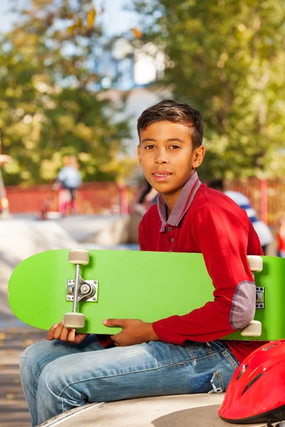 Хлопчик з зеленим скейтбордом — стокове фото
