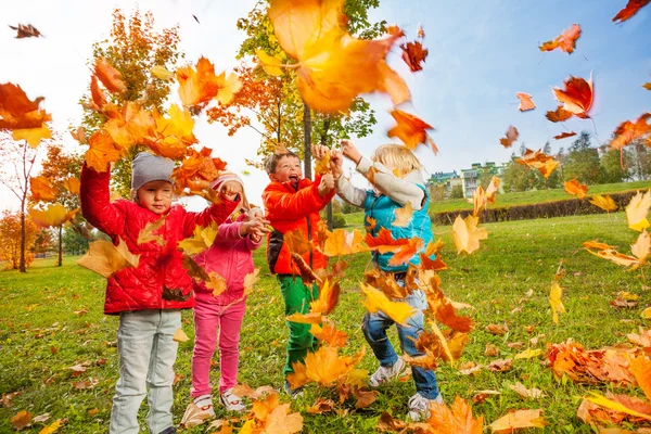 Crianças brincando com folhas amarelas — Fotografia de Stock