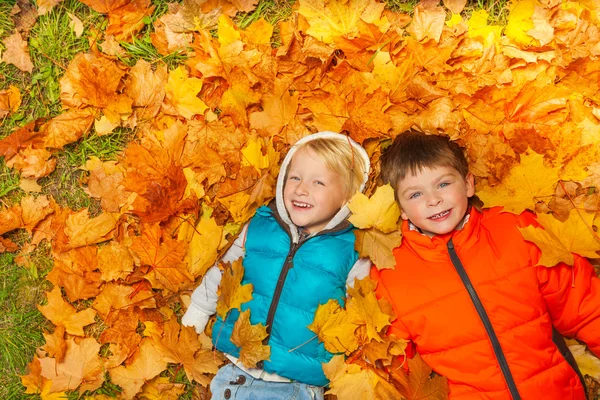 Boys laying on autumn leaves — Stock Photo, Image