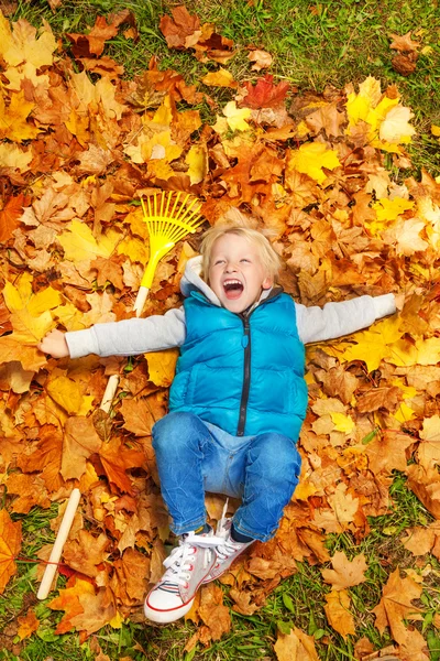 Blond boy laying on autumn leaves — Stock Photo, Image