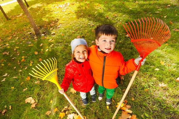 Niño y niña con rastrillos en el parque —  Fotos de Stock