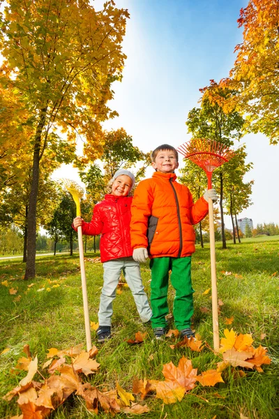 Jongen en meisje met harken in park — Stockfoto