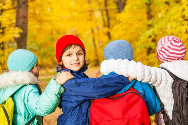 Costas de amigos abraçando e vestindo mochilas — Fotografia de Stock