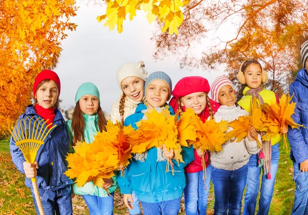 Niños felices con rastrillos y hojas —  Fotos de Stock