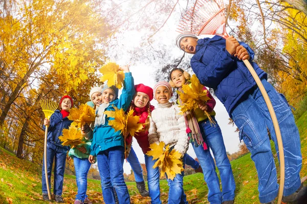 Niños felices con rastrillos y hojas — Foto de Stock