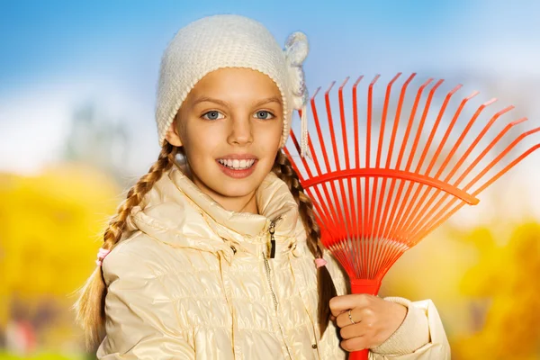 Smiling girl with red rake — Stock Photo, Image