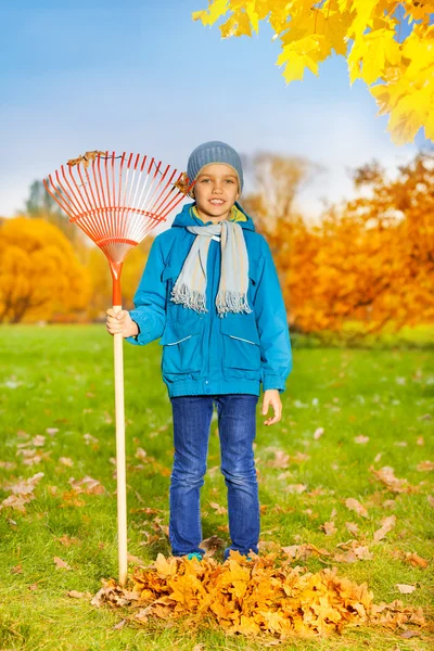 Smiling boy with rake in park — Stock Photo, Image