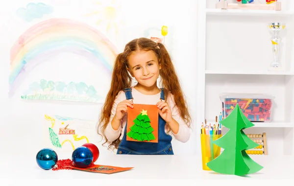 Girl holds card with Xmas tree — Stock Photo, Image