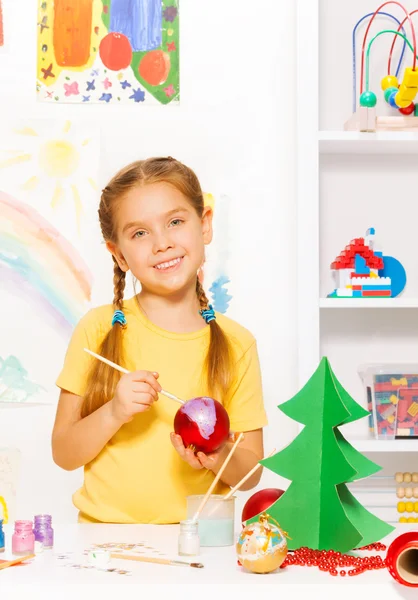 Happy girl paints New Year ball — Stock Photo, Image