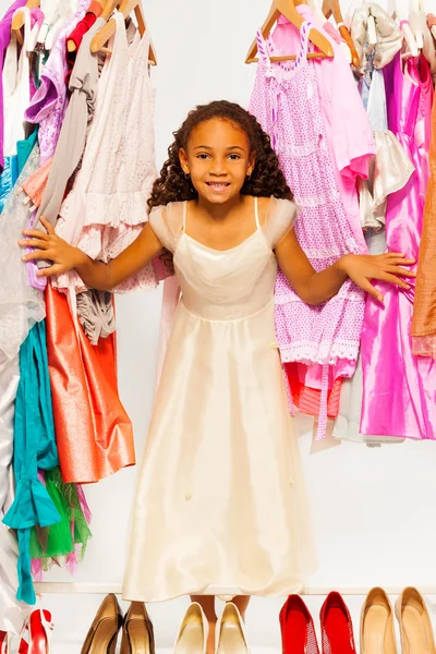 Dívka stojí mezi šaty — Stock fotografie