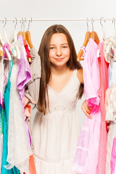 Flickan står bland kläder — Stockfoto