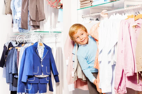 Pojke leker kurragömma i kläder butik — Stockfoto