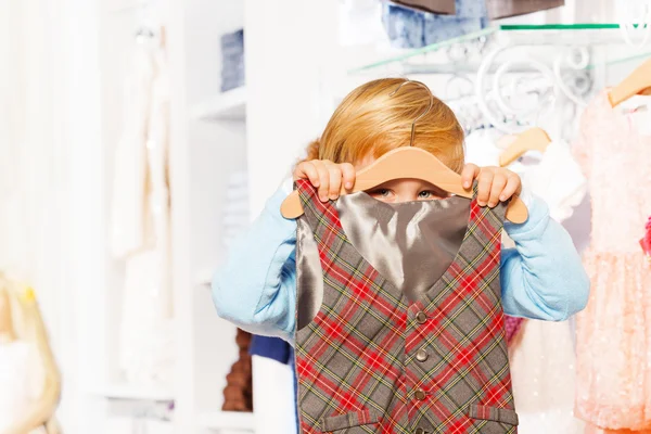 Boy gömmer sig bakom hängare och vest — Stockfoto