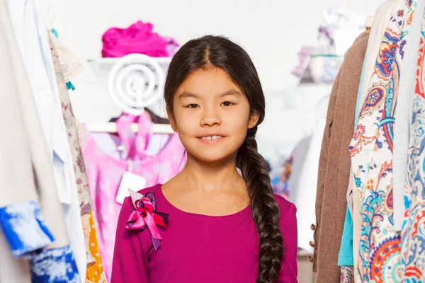 Aziatisch meisje tussen kleren in winkel — Stockfoto