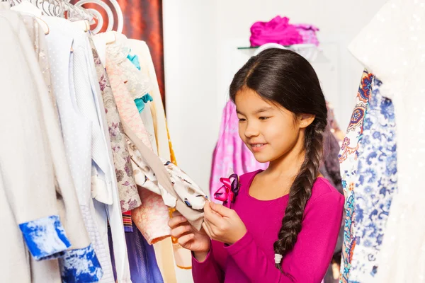 Asian girl with braid choosing clothes — Stock Photo, Image