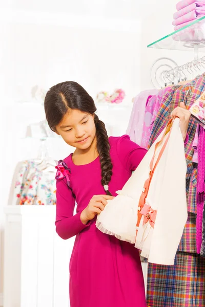 Asian girl holding chosen white sweater — Stock Photo, Image