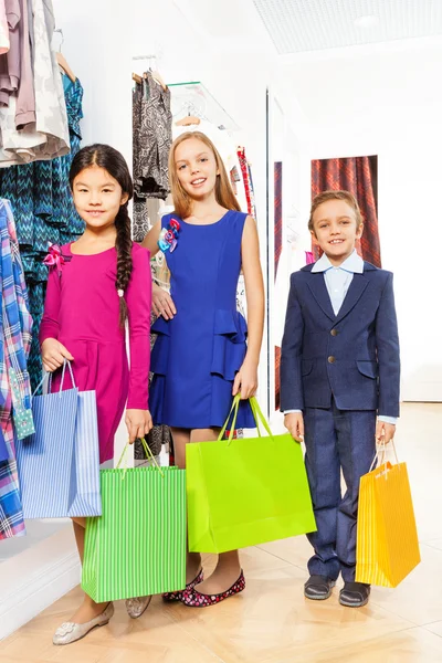 Dos niñas y un niño con bolsas de compras —  Fotos de Stock