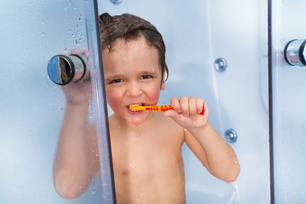 Escova de dentes de uso masculino na cabine do chuveiro — Fotografia de Stock