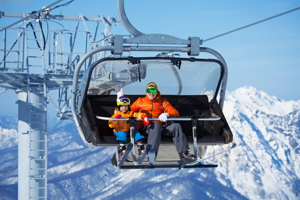 Father and boy sit in ski lift