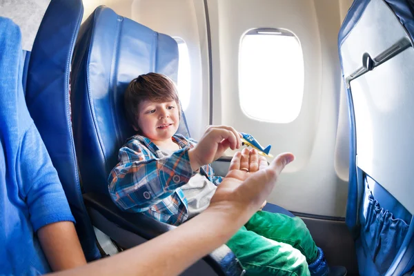 Junge nimmt Spielzeugflugzeug in Flugzeug — Stockfoto