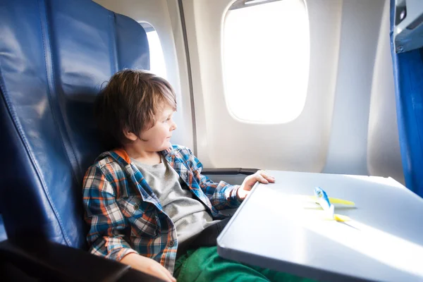 Niño se sienta en avión con modelo de juguete en la mesa —  Fotos de Stock