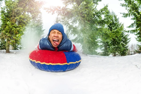 Boy on snow tube in winter forest — Stock Photo, Image