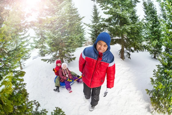 Menino puxando tubo de neve com crianças — Fotografia de Stock