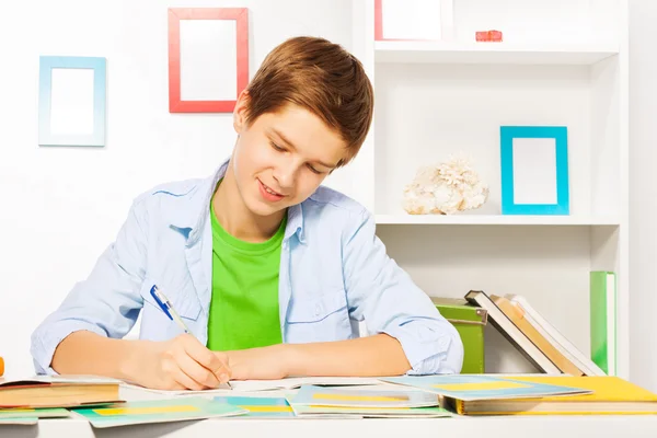 Smart handsome boy writes in textbook — Stock Photo, Image