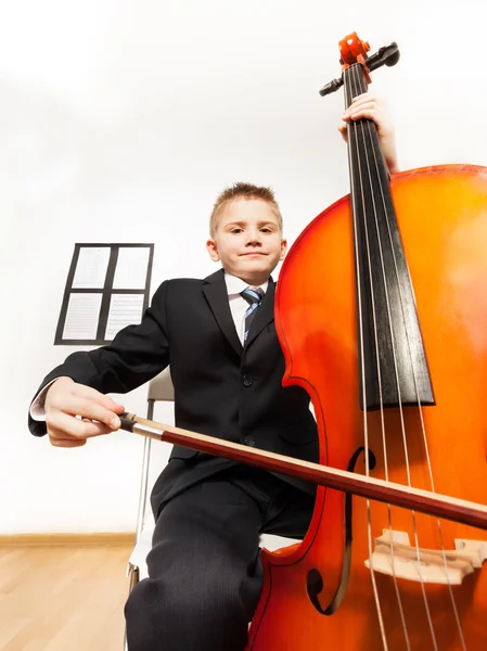 Chlapec hrát Violoncellový sedí na židli — Stock fotografie