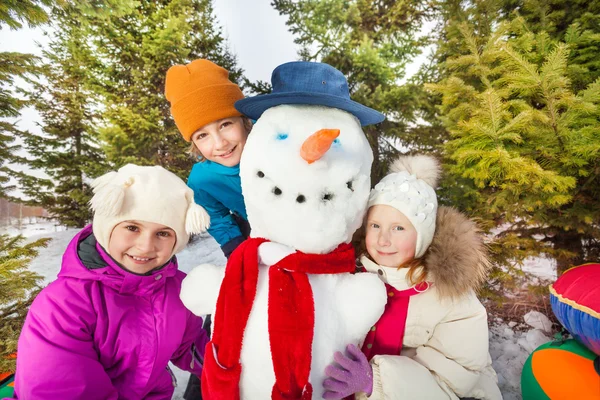 Children sitting close to snowman — Stok fotoğraf