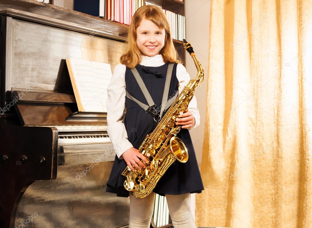 Happy girl holds alto saxophone