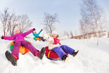 Happy girls and boy slide on tubes