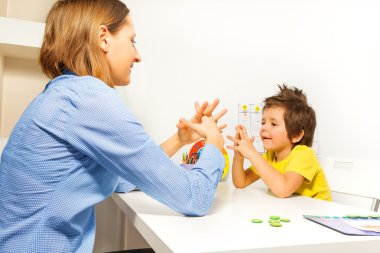 Boy exercises putting fingers with therapist