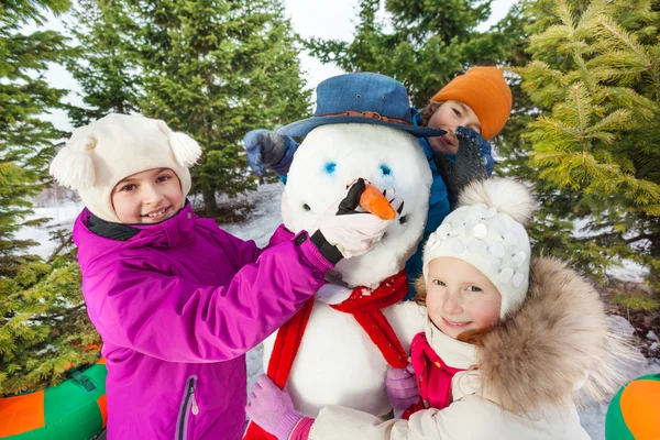 Glückliche Kinder bauen fröhlichen Schneemann — Stockfoto